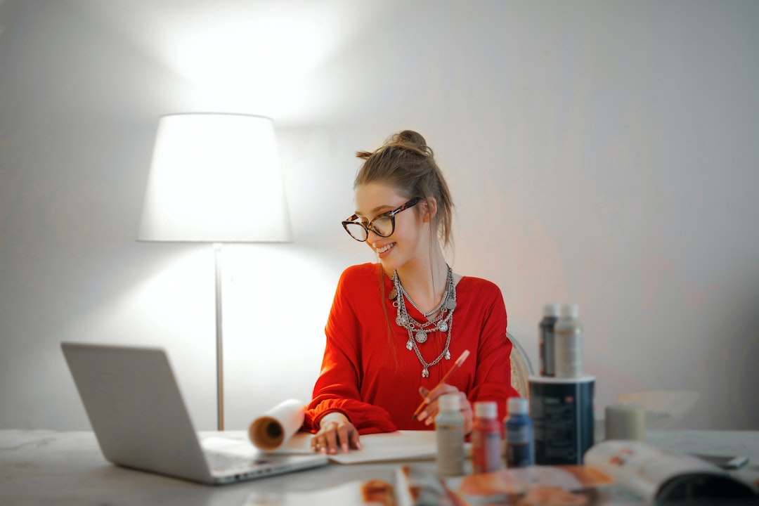 woman-in-red-long-sleeve-shirt-looking-at-her-laptop